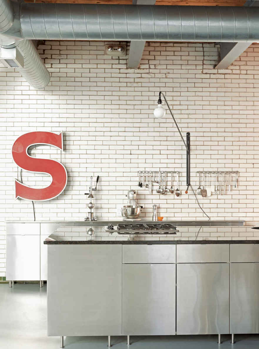 HIGH + LOW DONE RIGHT. Stainless steel cabinetry, arranged in an island configuration, looks high-end but isn’t, leaving room in the budget for a standout light fixture. Prouvé’s Potence swivel lamp is a classic.